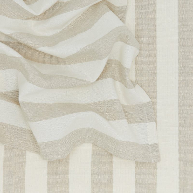 Close-up of beige and white striped fabric from Hawkins New York's Essential Striped Dinner Napkins (Set of 4), draped with soft folds, ideal for relaxed pieces or home basics.