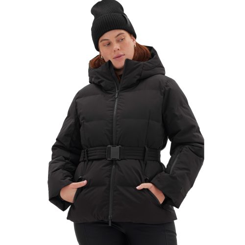 A person wearing the Hedy Puffer Jacket by Halfdays, which features mountain performance characteristics, a belted waist, and a hood, along with a black knit beanie, stands against a white background.